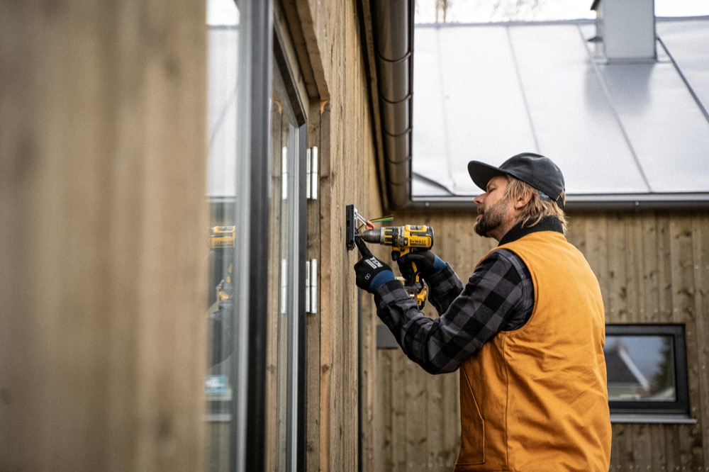 Installer mounting an entry device on a building exterior